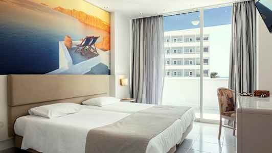 Hotellrum med dubbelsäng, stor väggbild av ett kustlandskap och balkong med utsikt. (AI-genererad text)