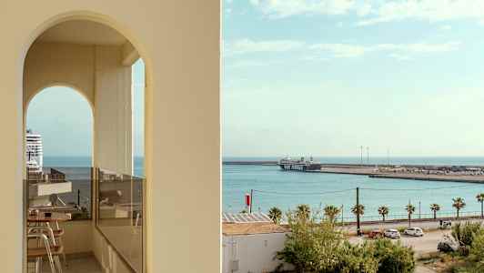 Vy mot havet med ett kryssningsfartyg och en färja vid hamnen, sett genom en bågformad öppning. (AI-genererad text)