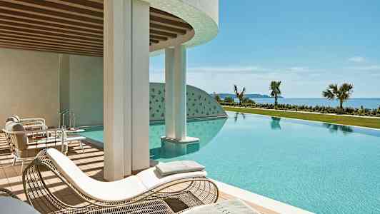 En utomhuspool med solstolar och utsikt mot havet. (AI-genererad text)