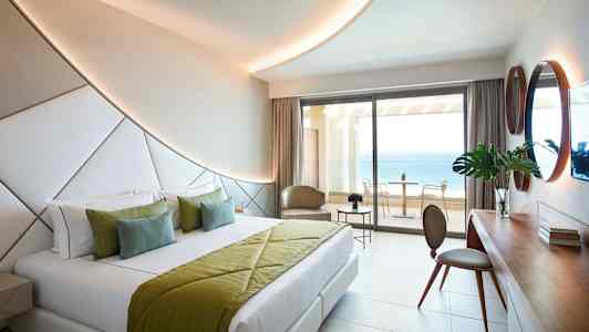 Modernt hotellrum med dubbelsäng och havsutsikt från balkongen. (AI-genererad text)