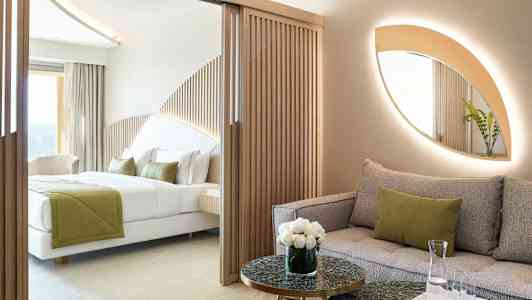 Modernt hotellrum med soffa och säng, inrett med naturliga färger och trädetaljer. (AI-genererad text)