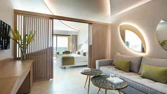 Ett hotellrum med en sittgrupp, bord och en säng i bakgrunden. (AI-genererad text)