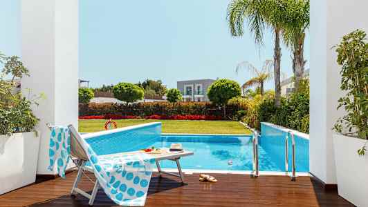 Utomhuspool omgiven av grönska och solstolar. (AI-genererad text)