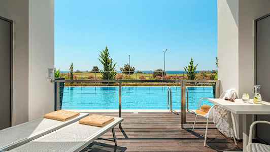 Utsikt från terrass över en pool, med strand och hav i bakgrunden. (AI-genererad text)