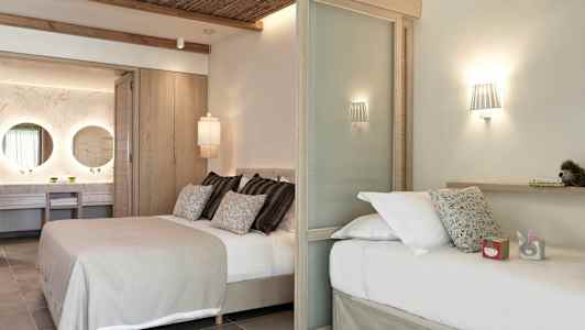 Ett modernt hotellrum med två sängar, dekorativ belysning och en synlig badrumsdel med två speglar. (AI-genererad text)