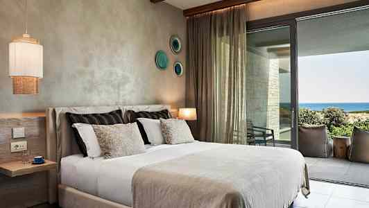 Ett hotellrum med en säng och utsikt över havet. (AI-genererad text)