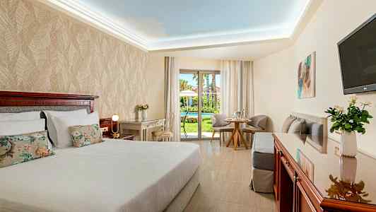 Hotellrum med dubbelsäng, skrivbord och sittgrupp. Utsikt mot en trädgård. (AI-genererad text)