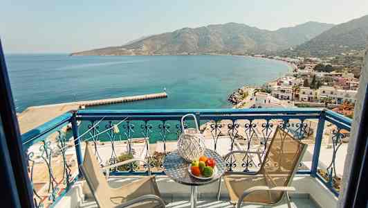 Balkong med utsikt över en bukt och en småstad vid havet. (AI-genererad text)