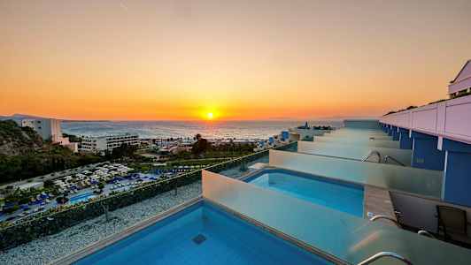 Utsikt över en rad privata pooler med solnedgång över havet i bakgrunden. (AI-genererad text)