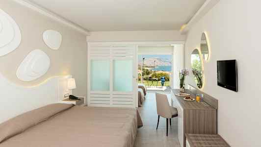 Hotellrum med två bäddar, skrivbord och TV. Utsikt mot grönska och havet. (AI-genererad text)