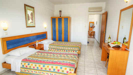 Ett hotellrum med två sängar, en garderob och en byrå med spegel. (AI-genererad text)