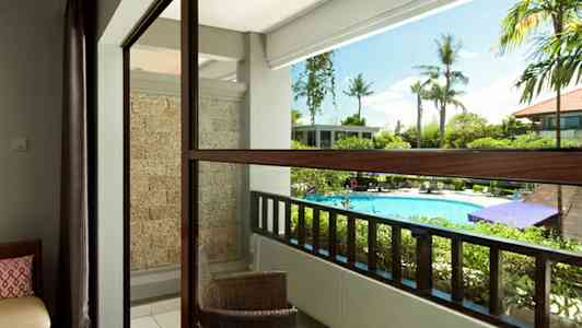 Balkong med utsikt över poolområdet, med utemöbler och grönska. (AI-genererad text)