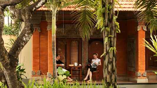 Två personer sitter på en veranda till ett hus dekorerat i traditionell stil. (AI-genererad text)