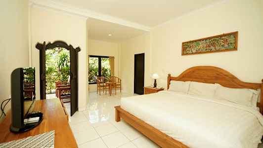 Ett väldesignat och ljust sovrum med en stor säng, trädetaljer och sittgrupp nära fönster med utsikt över grönska. (AI-genererad text)