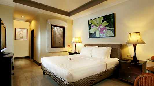 Ett sovrum med en stor säng, två sänglampor och en dekorativ tavla på väggen. (AI-genererad text)