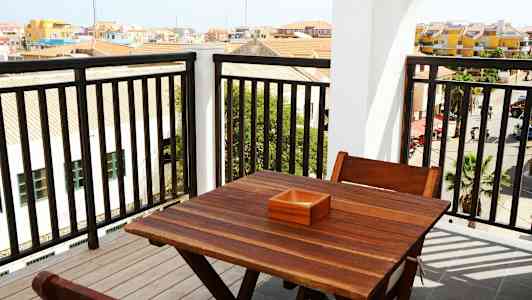 Utsikt från en balkong med ett träbord och stolar. (AI-genererad text)