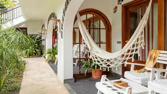 En uteplats med vita stolar, en hängmatta och gröna växter. (AI-genererad text)