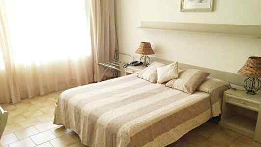 Ett hotellrum med en dubbelsäng, två nattduksbord och en lampa. (AI-genererad text)