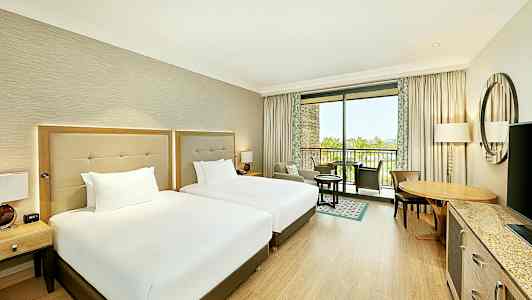 Hotellrum med två sängar och möbler, samt en balkong med utsikt. (AI-genererad text)