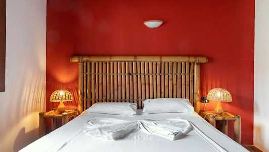 Ett sovrum med en bambusäng framför en röd vägg (AI-genererad text)