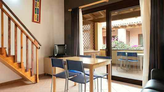 Ett rum med ett bord och stolar framför en glasdörr som leder ut till en terrass. (AI-genererad text)