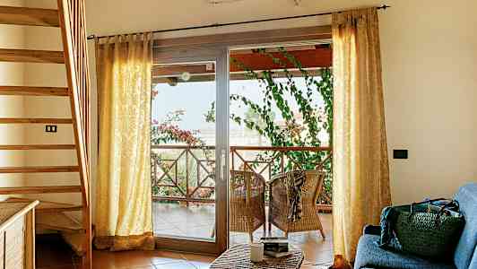 Interiör med trappa, soffhörna och terrass med sittplatser och gröna växter. (AI-genererad text)