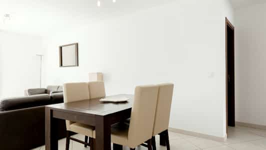 Ett modernt inrett vardagsrum med matbord och stolar i förgrunden. (AI-genererad text)