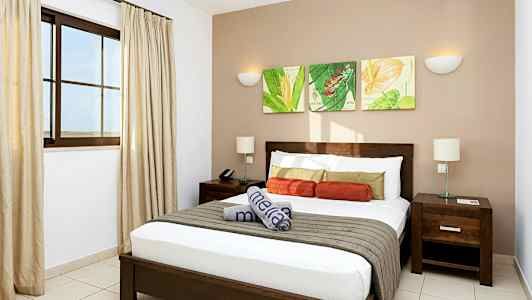 Ett modernt hotellrum med en dubbelsäng, nattduksbord och dekorativ väggkonst. (AI-genererad text)