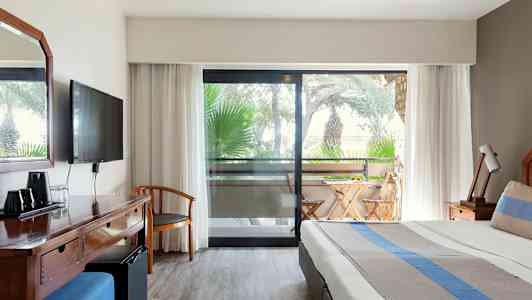 Bild av hotellrum med säng, skrivbord och balkong med utemöbler. (AI-genererad text)