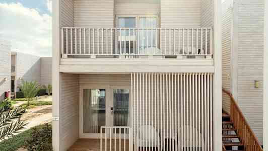 Två våningar med lagenhetsbalkonger i trädesign, omgivna av grönska. (AI-genererad text)