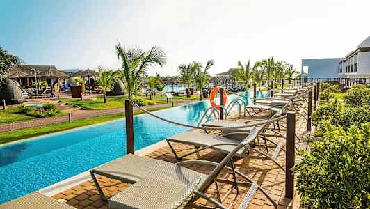 Solstolar vid en pool omgivna av palmer. (AI-genererad text)