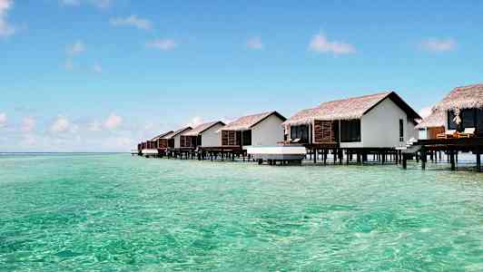 Stugor på pålar över turkost vatten. (AI-genererad text)