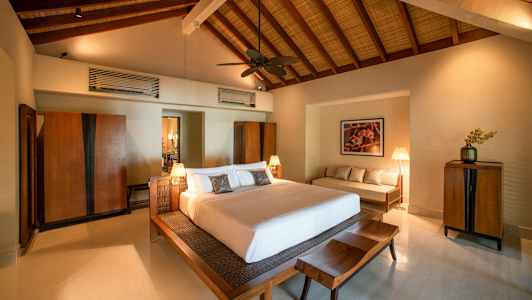 Ett sovrum med en stor säng, träinredning och högt tak. (AI-genererad text)