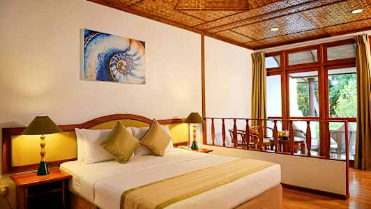 Ett hotellrum med en stor säng, två nattduksbord med lampor och en sittgrupp vid fönstret. (AI-genererad text)