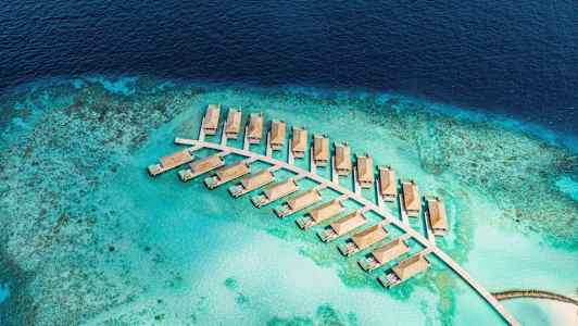 Luftvy av vattenvillor på en turkos lagun omgiven av hav. (AI-genererad text)