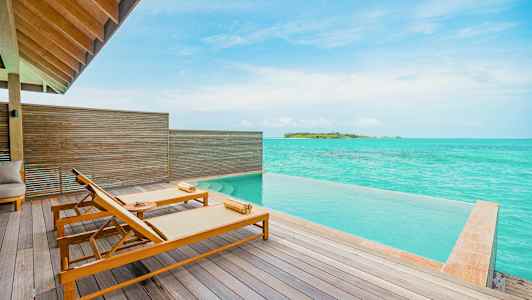 Terrass med två solstolar vid en infinitypool och utsikt över turkost hav. (AI-genererad text)