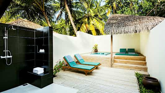 Utomhusdusch bredvid solstolar och jacuzzi på en träterass omgiven av palmer. (AI-genererad text)