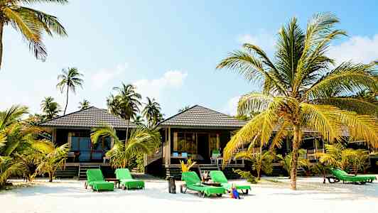 Strand med solstolar, palmer och strandhus. (AI-genererad text)