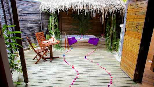 En utomhusterrass med ett bord, stolar, jacuzzi och dekorationer. (AI-genererad text)