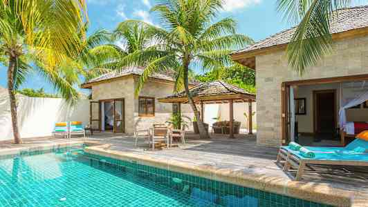 En villa med privat pool, omgiven av solstolar och tropiska palmer. (AI-genererad text)