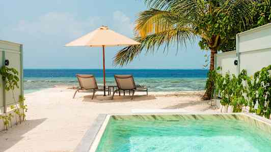 Solstolar under parasoll vid strand och hav. (AI-genererad text)