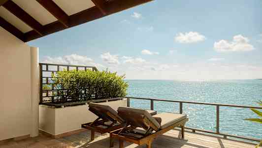 Två solstolar på en terrass med utsikt över havet. (AI-genererad text)