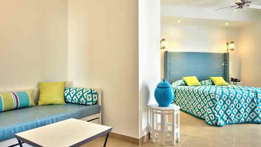 Ett hotellrum med säng, ljus inredning och dekorativa kuddar. (AI-genererad text)