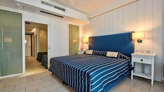 Sovrum med en dubbelsäng täckt med randigt överkast och två nattduksbord. (AI-genererad text)