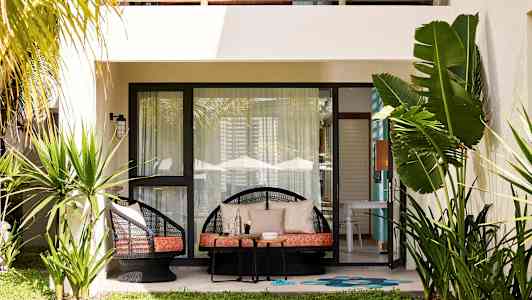 En terrass med fåtöljer, bord och växter framför en bostad. (AI-genererad text)