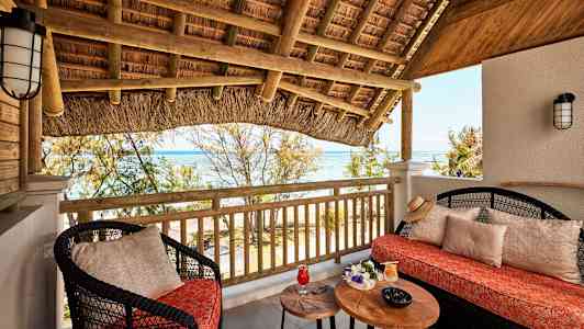 Terrass med sittmöbler, bord och utsikt över havet. (AI-genererad text)