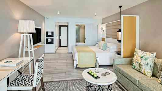 Ett hotellrum med modern inredning, säng, skrivbord, soffa och ett soffbord. (AI-genererad text)