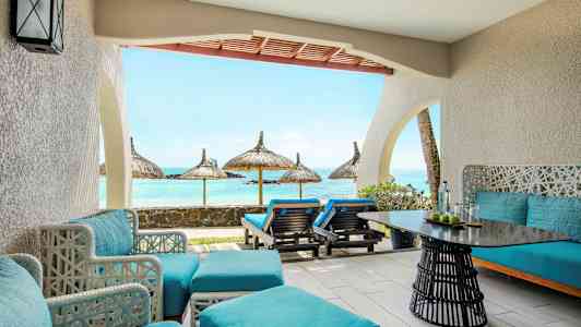 En terrass med blå sittmöbler och utsikt mot havet med parasoller. (AI-genererad text)