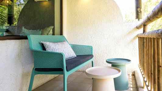 Uteplats med en grön stol och små bord. (AI-genererad text)