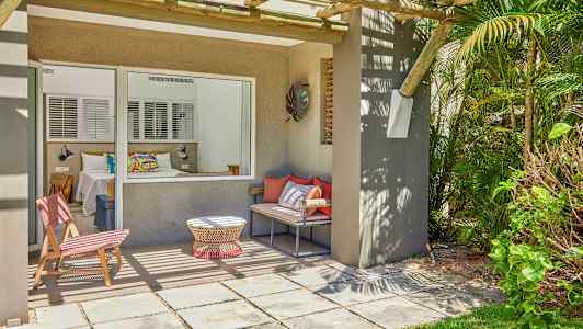 En terrass med sittplatser och utsikt mot ett sovrum genom ett stort fönster. (AI-genererad text)